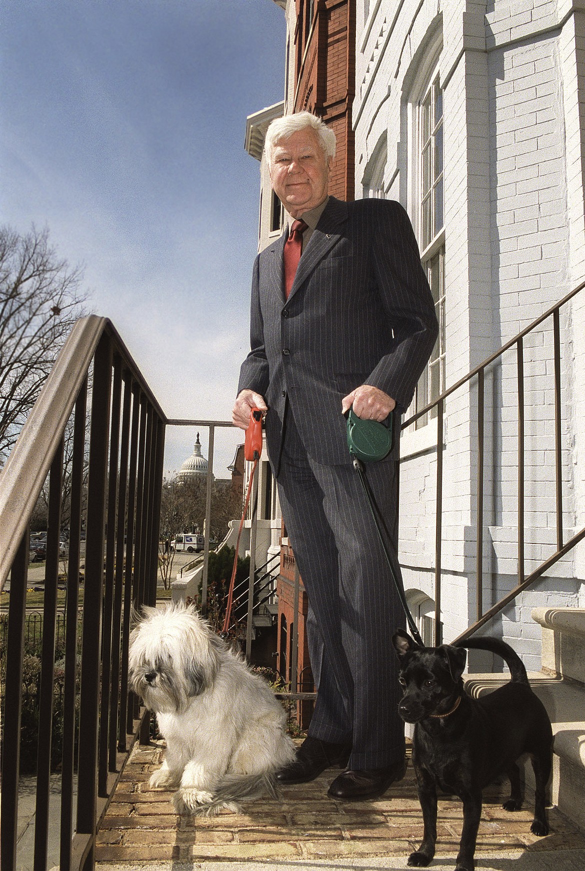 FILE - In this March 6, 2002, file photo, with the Capitol in the background, former Montana Sen. John Melcher stands with his dogs Ben, left, and Max outside his Washington home. Melcher, a Montana Democrat who narrowly lost a bid for a third term in 1988 just days after a wilderness bill he championed was vetoed, has died. He was 93. (AP Photo/Evan Vucci, File)