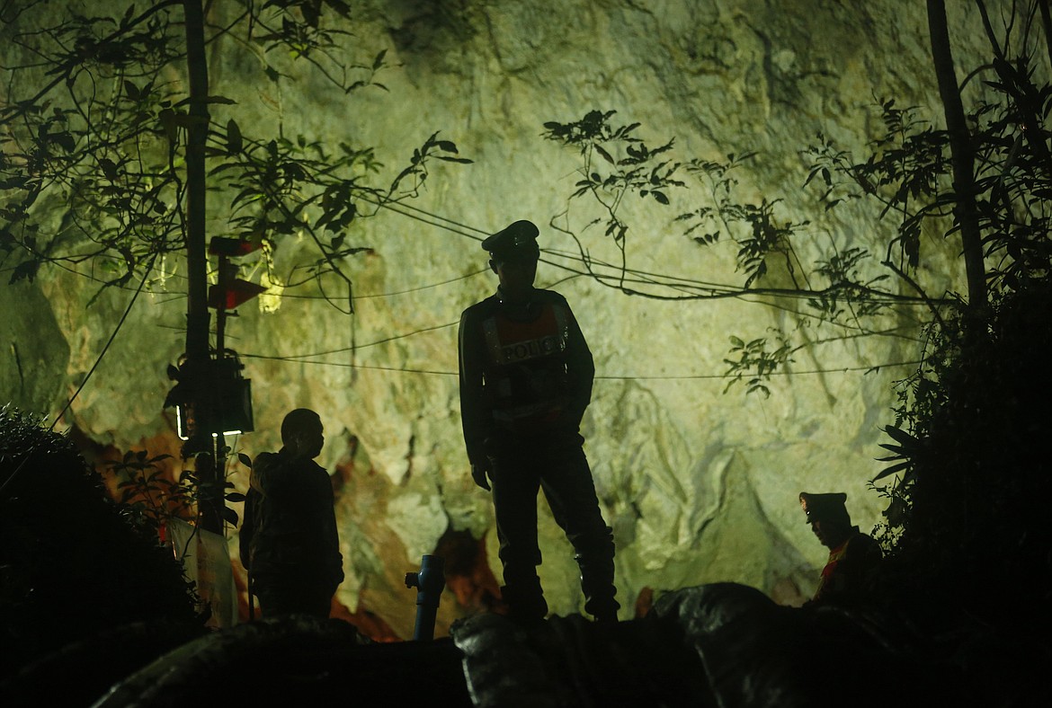 Thai police stand in front of the entrance to a cave complex where 12 boys and their soccer coach went missing, in Mae Sai, Chiang Rai province, in northern Thailand, Monday, July 2, 2018. Rescue divers are advancing in the main passageway inside the flooded cave in northern Thailand where the boys and their coach have been missing more than a week. (AP Photo/Sakchai Lalit)