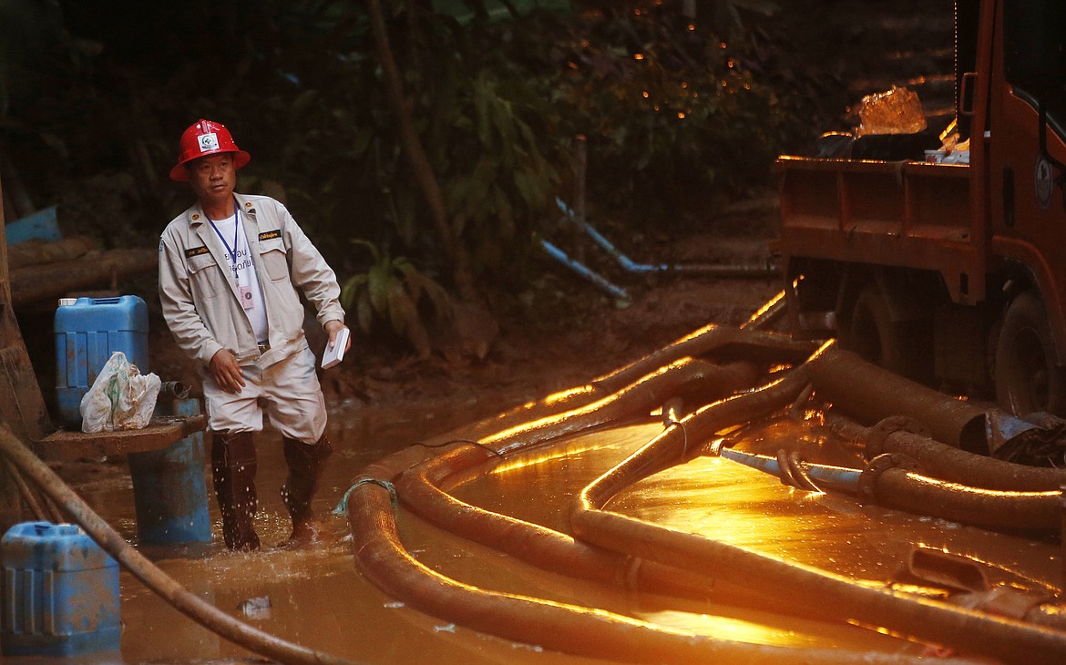 A rescuer makes his way down muddy steps past water pump hoses at the entrance to a cave complex where 12 soccer team members and their coach went missing, Monday, July 2, 2018, in Mae Sai, Chiang Rai province, in northern Thailand. Rescue divers are advancing in the main passageway inside the flooded cave in northern Thailand where the boys and their coach have been missing more than a week. (AP Photo/Sakchai Lalit)