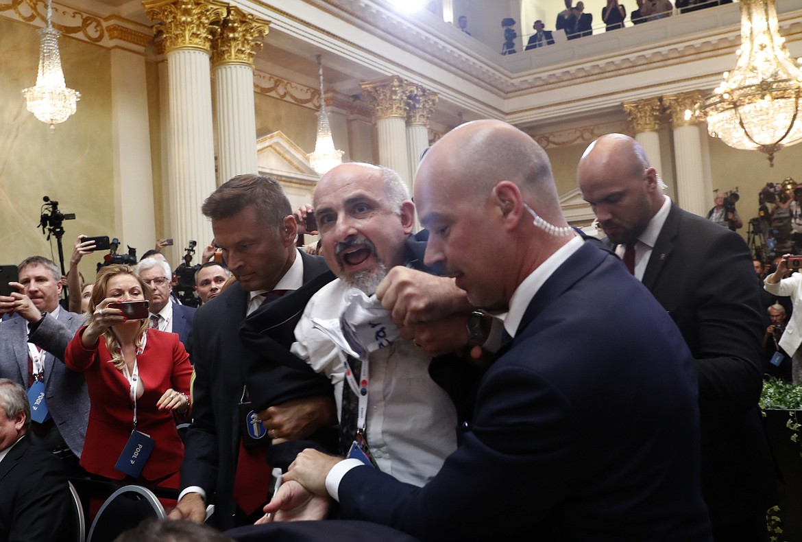 A man is taken out of the venue prior to a press conference after the meeting of U.S. President Donald Trump and Russian President Vladimir Putin at the Presidential Palace in Helsinki, Finland, Monday, July 16, 2018. (AP Photo/Pablo Martinez Monsivais)