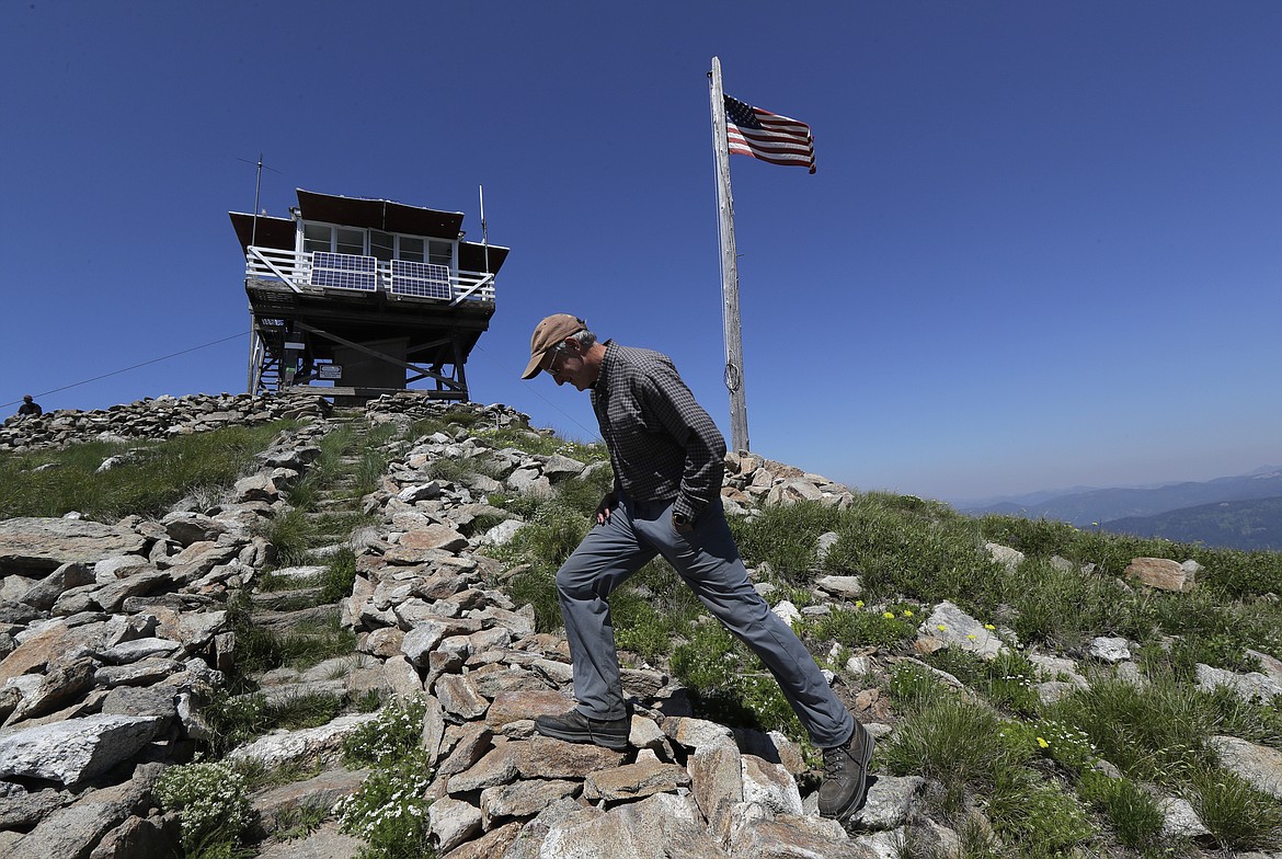 In this Wednesday, July 18, 2018, photo, Tom VandeWater walks up the stone steps to the Coolwater Fire Lookout in the Nez Perce-Clearwater National Forests near Lowell, Idaho. VandeWater, from Canton, N.Y., has staffed the lookout each summer for many years for the U.S. Forest Service. Fire-lookout towers, perched atop remote, craggy peaks across the U.S. West, may seem like quaint reminders of an era before satellites, smartphones and jet-propelled air tankers, but the structures and the people who staff them play a crucial role in the nation's front-line efforts to stop wildfires. (AP Photo/Ted S. Warren)