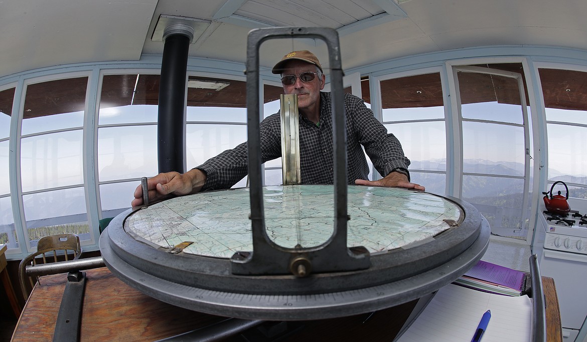 In this Wednesday, July 18, 2018, photo, Tom VandeWater demonstrates how he uses a device called the Osborne Fire-Finder to pinpoint the location of any smoke or fires he spots from the Coolwater Fire Lookout in the Nez Perce-Clearwater National Forests near Lowell, Idaho. (AP Photo/Ted S. Warren)