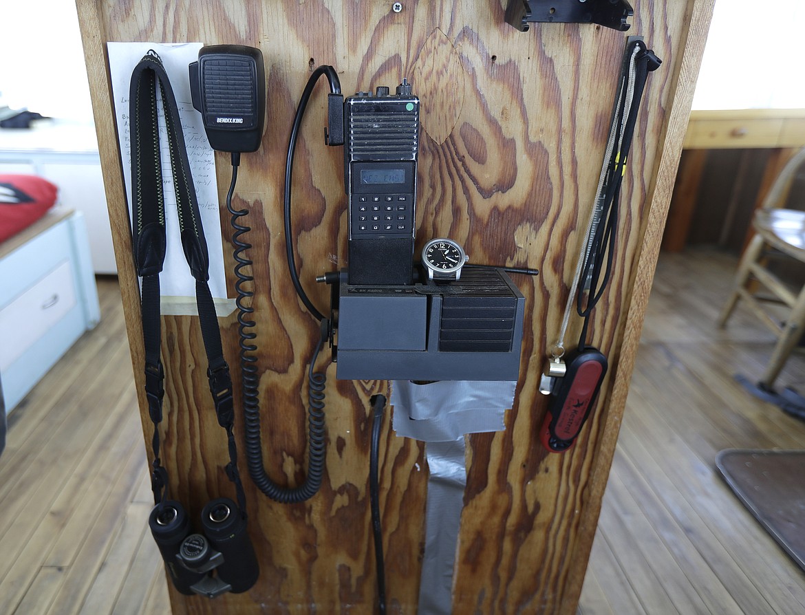 In this Wednesday, July 18, 2018, photo, a radio, binoculars, and other tools used by Tom VandeWater, who staffs the Coolwater Fire Lookout each summer for the U.S. Forest Service, are displayed in the Nez Perce-Clearwater National Forests near Lowell, Idaho. Fire-lookout towers, perched atop remote, craggy peaks across the U.S. West, may seem like quaint reminders of an era before satellites, smartphones and jet-propelled air tankers, but the structures and the people who staff them play a crucial role in the nation's front-line efforts to stop wildfires. (AP Photo/Ted S. Warren)