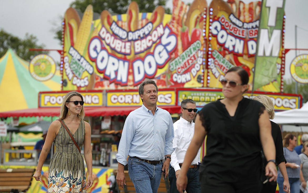 Montana Gov. Steve Bullock, center, walks down the main concourse during a visit to the Iowa State Fair, Thursday, Aug. 16, 2018, in Des Moines, Iowa. (AP Photo/Charlie Neibergall)