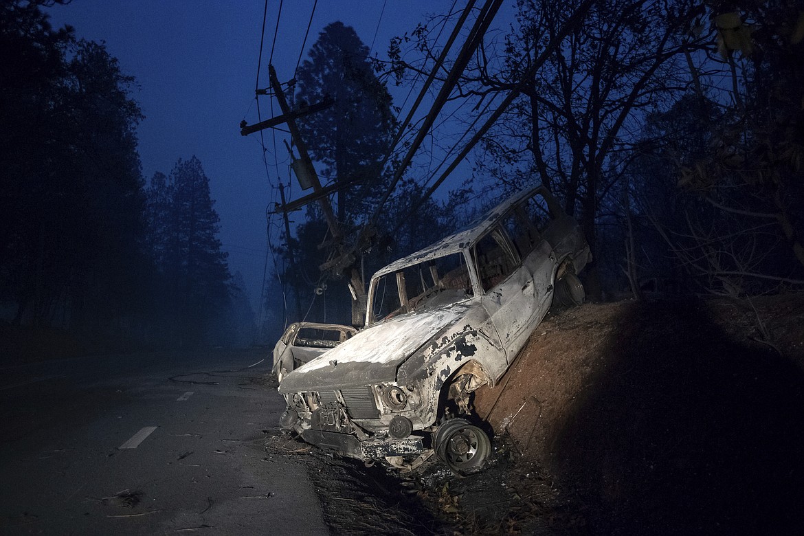 A scorched vehicle rests on a roadside as the Camp Fire tears through Paradise, Calif., on Thursday, Nov. 8, 2018. Tens of thousands of people fled a fast-moving wildfire Thursday in Northern California, some clutching babies and pets as they abandoned vehicles and struck out on foot ahead of the flames that forced the evacuation of an entire town and destroyed hundreds of structures. (AP Photo/Noah Berger)