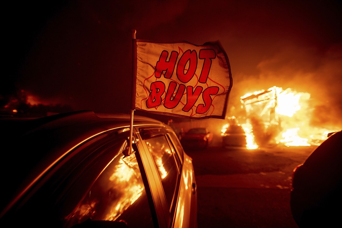 Flames consume a car dealership as the Camp Fire tears through Paradise, Calif., on Thursday, Nov. 8, 2018. Tens of thousands of people fled a fast-moving wildfire Thursday in Northern California, some clutching babies and pets as they abandoned vehicles and struck out on foot ahead of the flames that forced the evacuation of an entire town and destroyed hundreds of structures. (AP Photo/Noah Berger)