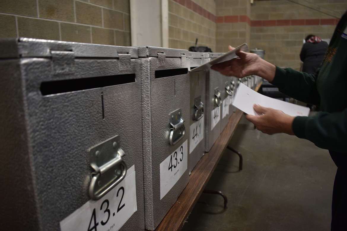 An election worker is seen inserting a ballot into a locked ballot box at the Montana Pavilion at MetraPark on election day, Tuesday, Nov. 6, 2018, in Billings, Mont. (AP Photo/Matthew Brown)