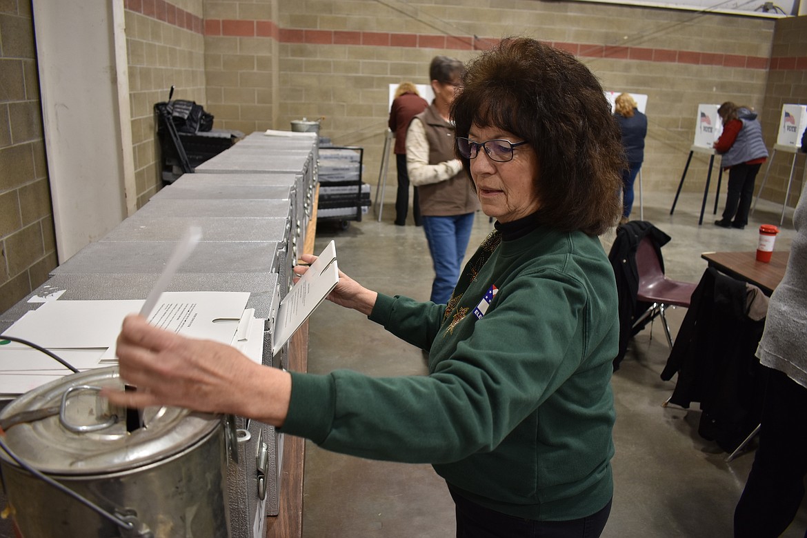 Election worker Rose Crowley drops a ballot into a ballot box at the Montana Pavilion at MetraPark on election day, Tuesday, Nov. 6, 2018, in Billings, Mont. (AP Photo/Matthew Brown)