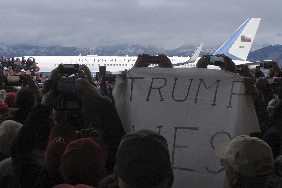 A protester holds up a sign before President Donald Trump speaks at a campaign rally at Bozeman Yellowstone International Airport, Saturday, Nov. 3, 2018, in Belgrade, Mont. (AP Photo/Matt Volz)