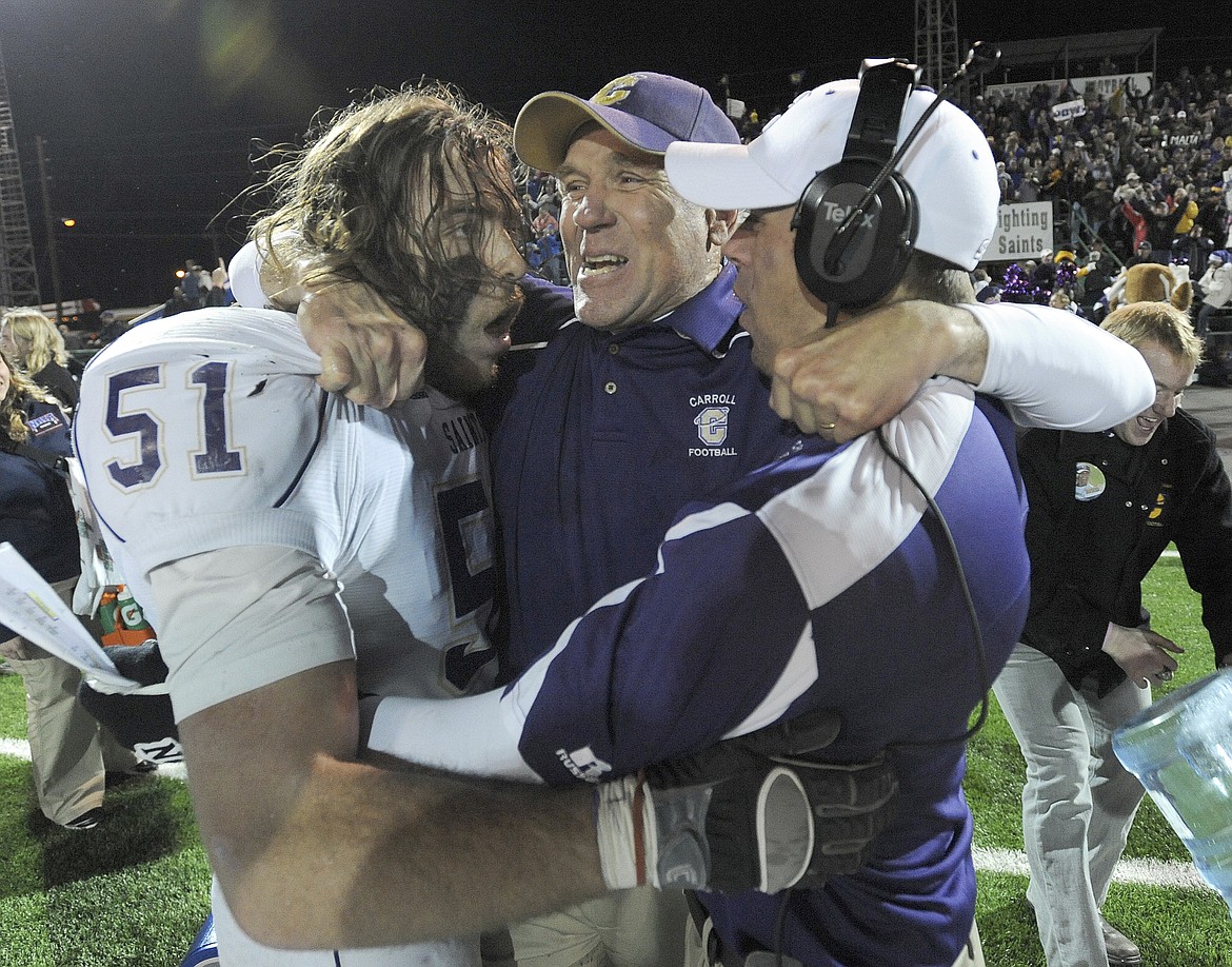 FILE - In this Dec. 18, 2010, file photo, Carroll College coach Mike Van Diest, center, is hugged by linebacker Lynn Mallory (51) and another coach after Carroll College defeated Sioux Falls in the NAIA college football championship game at Brannon Field in Rome, Ga. Van Diest announced his retirement Monday, Nov. 12, 2018, after 20 seasons and six NAIA national championships at the Helena school. (AP Photo/Erik S. Lesser, file)