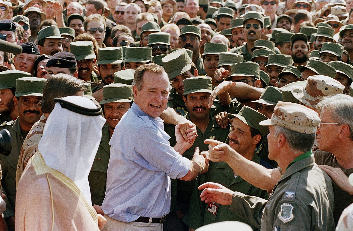 FILE - In this Nov. 22, 1990 file photo, President George H.W. Bush is greeted by Saudi troops and others as he arrives in Dhahran, Saudi Arabia, for a Thanksgiving visit. Bush died at the age of 94 on Friday, Nov. 30, 2018, about eight months after the death of his wife, Barbara Bush. (AP Photo/J. Scott Applewhite, File)