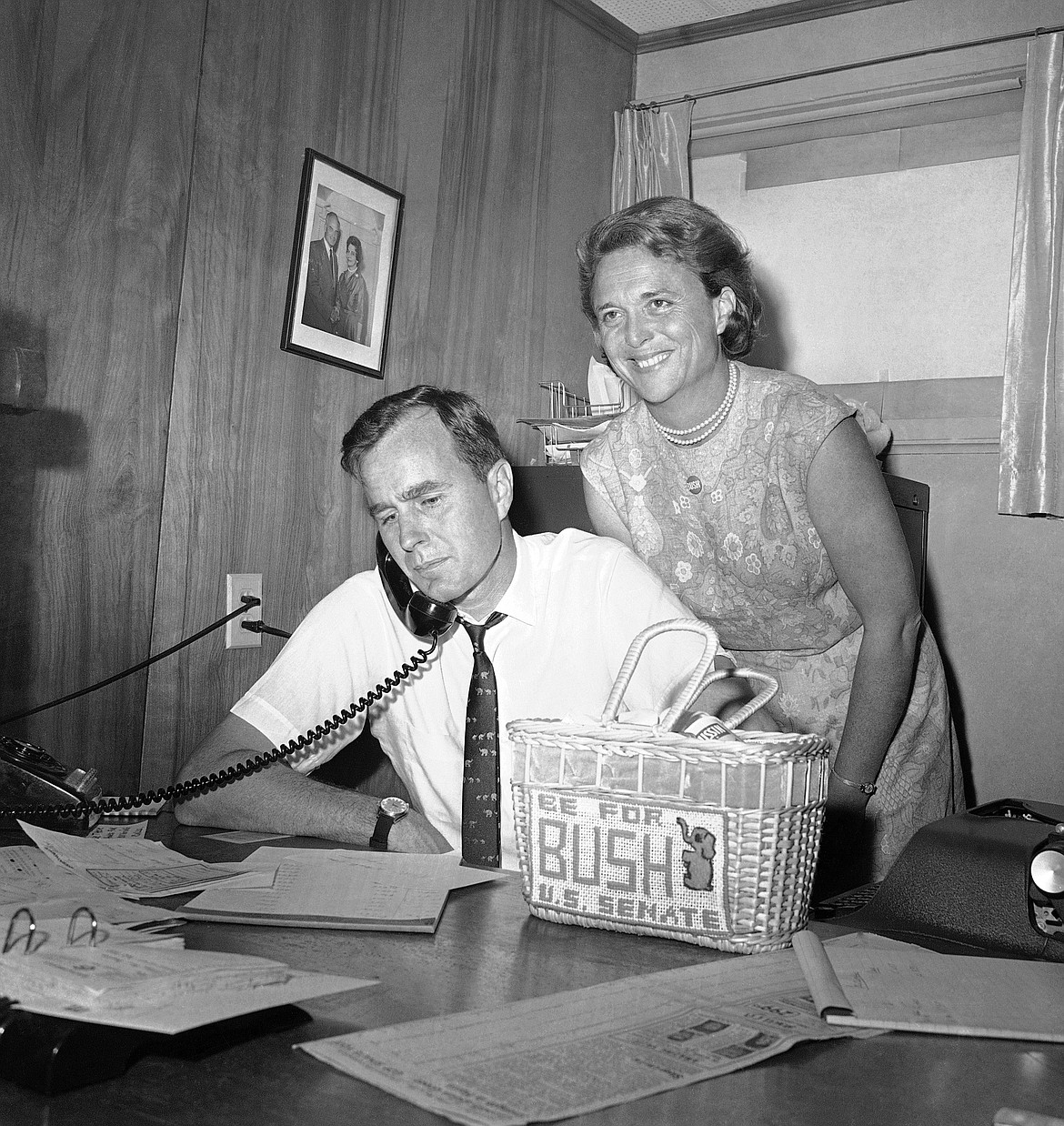 FILE - In this June 6, 1964, file photo George H.W. Bush, candidate for the Republican nomination for the U.S. Senate, gets returns by phone at his headquarters in Houston, as his wife Barbara, smiles at the news. Bush died at the age of 94 on Friday, Nov. 30, 2018, about eight months after the death of his wife, Barbara Bush. (AP Photo/Ed Kolenovsky, File)