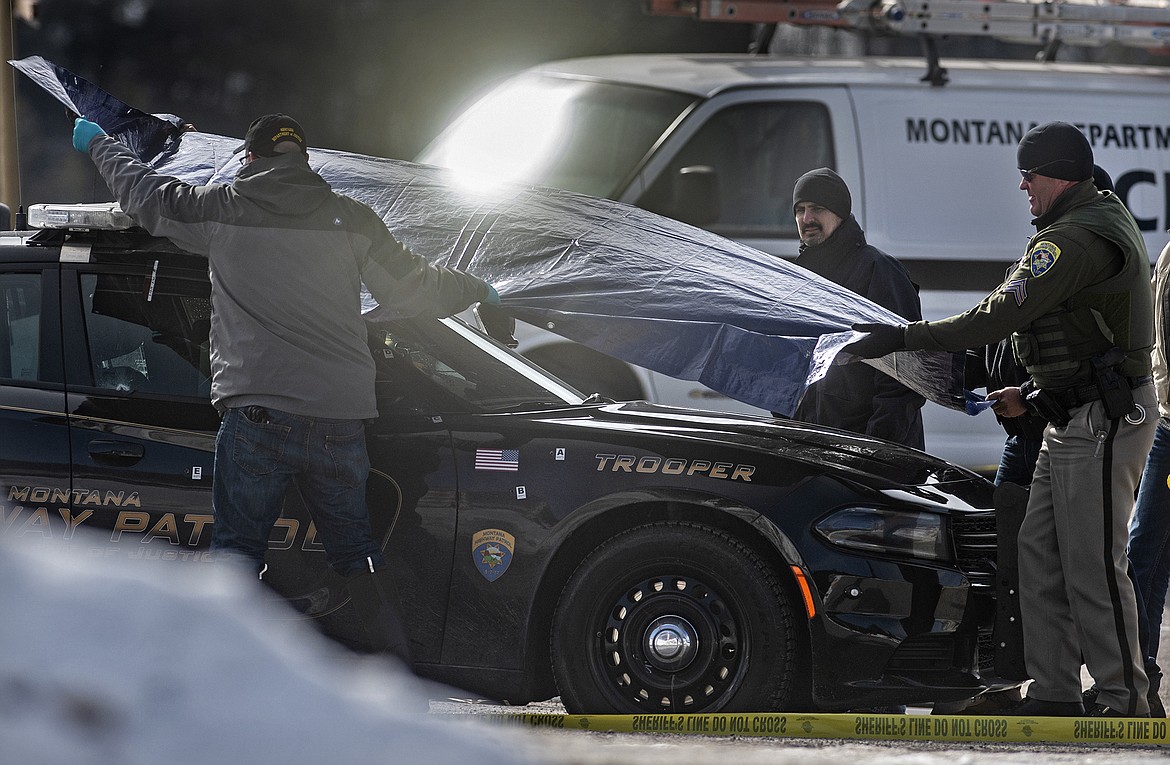 Law enforcement cover Montana State Trooper Wade Palmer&#146;s car at the scene of the shooting near the Evaro Bar on Friday, March 15, 2019, in Missoula, Mont. Palmer, who was investigating an earlier shooting, was himself shot and critically injured early Friday after finding the suspect&#146;s vehicle, leading authorities to launch an overnight manhunt that ended in the arrest of a 29-year-old man, officials said. (Tommy Martino/The Missoulian via AP)