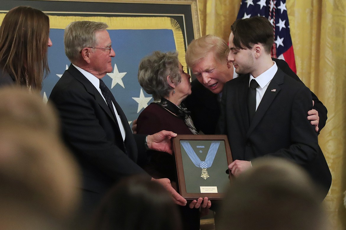 President Donald Trump awards the Medal of Honor to Army Staff Sgt. Travis Atkins and leans forward to join Atkin&#146;s son Trevor Oliver, right, and his parents John and Elaine Atkins of Bozeman, Mont., after accepting the posthumous recognition for conspicuous gallantry in Iraq in June 2007, in the East Room of the White House, Wednesday March 27, 2019, in Washington.  (AP Photo/Manuel Balce Ceneta)