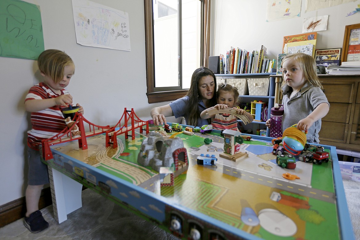 In this Thursday, June 6, 2019 photo, Sarah Montoya plays with her daughter, Walden, and twins Farallon, right, and Nicasio, left, at their home in San Francisco. During last year's deadly Camp Fire, which killed 85 people and destroyed 14,000 homes, smoke from the blaze inundated a San Francisco neighborhood roughly 170 miles away where Montoya lives with her husband, Trevor McNeil, and their three children. All three children have respiratory problems suspected to be asthma. But when the smoke from the Camp Fire filled the air for two weeks, the family was unable to find child-sized face masks to protect them or an air filter to clear the air in their house. (AP Photo/Eric Risberg)