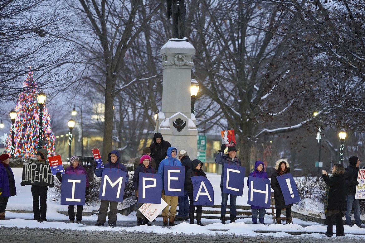 Protesters hold up signs to traffic on Park Square in Pittsfield, Mass., supporting impeachment articles against President Trump to be passed in n Congress, Tuesday, December 17, 2019. (Ben Garver/The Berkshire Eagle via AP)
