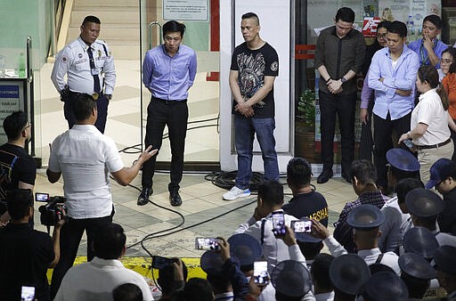 Former security guard Archie Paray, center, listens to San Juan Mayor Francis Zamora, left, shortly after releasing all his hostages at the V-mall in Manila, Philippines on Monday, March 2, 2020. Officials say a recently dismissed security guard has released his hostages and walked out of a Philippine shopping mall, ending a daylong hostage crisis. (AP Photo/Aaron Favila)