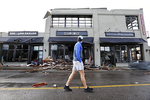 A man walks by buildings destroyed by storms Tuesday, March 3, 2020, in Nashville, Tenn. Tornadoes ripped across Tennessee early Tuesday, shredding buildings and killing multiple people. (AP Photo/Mark Humphrey)