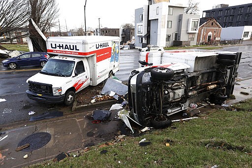 Damaged trucks sit on a sidewalk as well as the street following a deadly tornado, Tuesday, March 3, 2020, in Nashville, Tenn. Tornadoes ripped across Tennessee early Tuesday, shredding buildings and killing multiple people.  (AP Photo/Mark Humphrey)