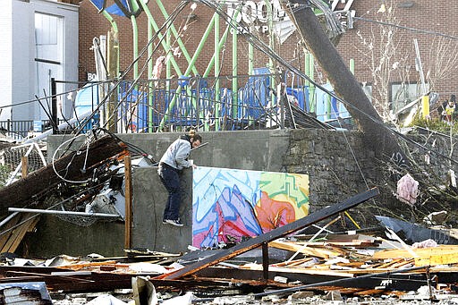A man climbs through storm debris Tuesday, March 3, 2020, in Nashville, Tenn. Tornadoes ripped across Tennessee early Tuesday, shredding buildings and killing multiple people.  (AP Photo/Mark Humphrey)