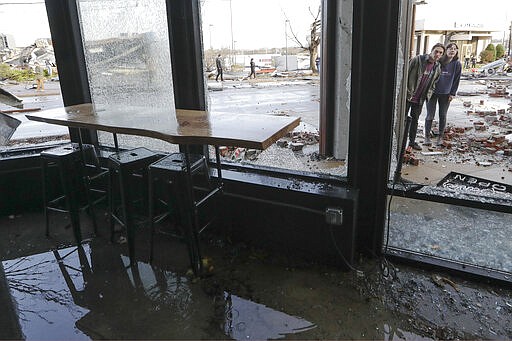 People look in a restaurant damaged by storms Tuesday, March 3, 2020, in Nashville, Tenn. Tornadoes ripped across Tennessee early Tuesday, shredding buildings and killing multiple people.  (AP Photo/Mark Humphrey)