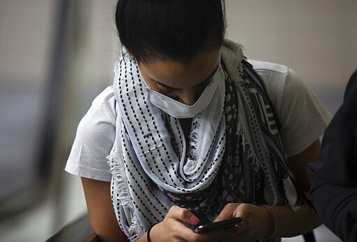 A traveller wearing a mask at Johannesburg's OR Tambo International Airport, Sunday, March 1, 2020. South Africa's Health Minister Zweli Mkhize has laid out South Africa's plan to evacuate 151 South African citizens from Wuhan, China following the outbreak of the coronavirus as well as government's readiness to deal with a potential outbreak. (AP Photo/Denis Farrell)