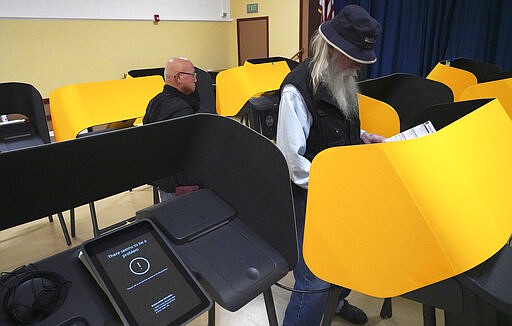 Early voter Bill Bassett, right, casts his ballot at one of the few working electronic voting machines at the Ranchito Avenue Elementary School in the Panorama City section of Los Angeles on Monday, March 2, 2020. Major changes to the way people vote has election advocates on edge as Californians cast ballots in the Democratic presidential contest and other primary races. (AP Photo/Richard Vogel)