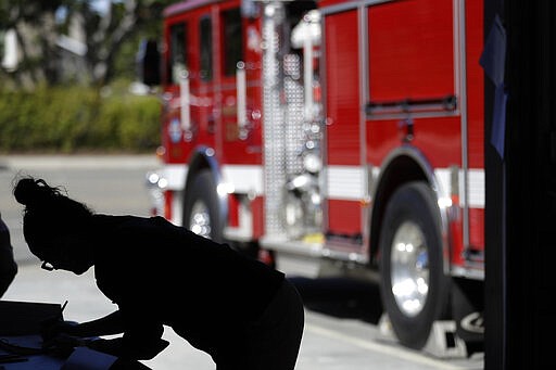 A woman registers before voting at a polling place in a fire station during primary elections Tuesday, March 3, 2020, in Encinitas, Calif. California officials bracing for long lines are urging patience as voters cast ballots on &quot;Super Tuesday&quot; in what could be record turnout for a presidential primary election. (AP Photo/Gregory Bull)