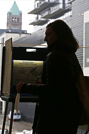 A voter silhouetted against the city hall clock tower leaves the voting booth with ballot in hand at the downtown library polling site in Minneapolis as part of Minnesota's Super Tuesday presidential nomination primary March 3, 2020. (AP Photo/Jim Mone)