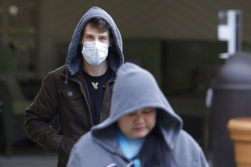 A man wearing a mask walks away from the entrance of the Life Care Center in Kirkland, Wash., near Seattle, Tuesday, March 3, 2020. The facility has been tied to several confirmed cases of the COVID-19 coronavirus. (AP Photo/Ted S. Warren)