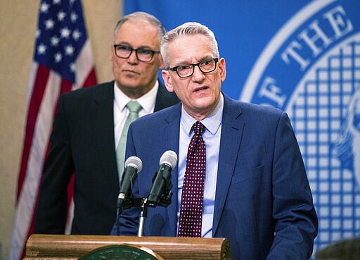 Dr. John Wiesman, secretary of the Washington State Department of Health, right, speaks about the measures done so far to prevent spreading and safety on Monday, March 2, 2020 in Olympia, Wash. Gov. Jay Inslee is in the background. (Amanda Snyder/The Seattle Times via AP)