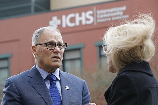 Washington Gov. Jay Inslee, left, talks with Washington State Health Officer Dr. Kathy Lofy, right, Tuesday, March 3, 2020, following a private tour of the International Community Health Services Clinic in Seattle's International District. Inslee urged people to wash hands frequently and practice other measures of health hygiene during the COVID-19 Coronavirus outbreak and told people to stay home from work and public events if they don't feel well or have any symptoms of illness. (AP Photo/Ted S. Warren)