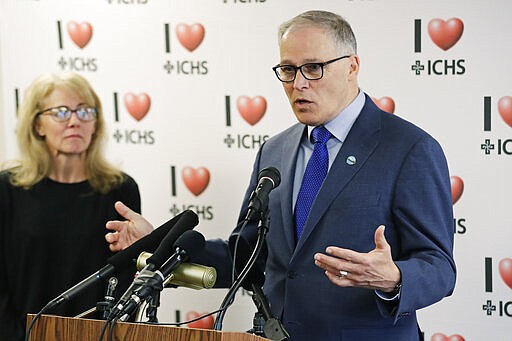 Washington Gov. Jay Inslee, right, talks with reporters as Washington State Health Officer Dr. Kathy Lofy looks on at left, Tuesday, March 3, 2020, following a private tour of the International Community Health Services Clinic in Seattle's International District. Inslee urged people to wash hands frequently and practice other measures of health hygiene during the COVID-19 Coronavirus outbreak and told people to stay home from work and public events if they don't feel well or have any symptoms of illness. (AP Photo/Ted S. Warren)