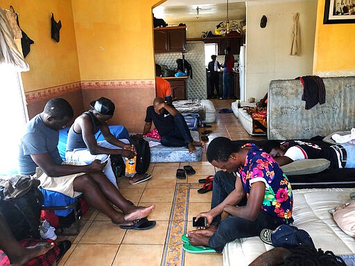 FILE - In this July 28, 2019, file photo, Cameroonians wait in a rented apartment in Tijuana, Mexico, until their names are called to claim asylum in the U.S.  President Donald Trump isn't the only world leader making it virtually impossible for many Africans to get asylum in the United States.  Ecuador is closing its doors as one of the few countries in North and South America to welcome African visitors, depriving them of a starting point for their dangerous journeys north by land.  (AP Photo/Elliot Spagat, File)