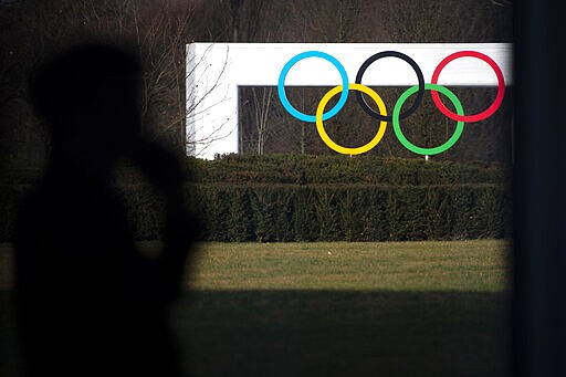 A journalist walks past the Olympic Rings prior to a meeting of the International Olympic Committee (IOC) at the Olympic House in Lausanne, Switzerland, Tuesday, March 3, 2020. The International Executive Committee holds an Executive Board meeting in Lausanne and is expected to discuss the impact of the coronavirus on Tokyo 2020. (Laurent Gillieron/Keystone via AP)