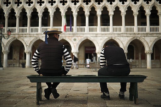 Gondoliers chat as they wait for customers near St. Mark's square in Venice, Italy, Tuesday, March 3, 2020. G-7 countries say they are ready to take action to cushion the economic impacts of the new coronavirus outbreak, a statement that comes after a few days of wild market swings. (AP Photo/Francisco Seco)