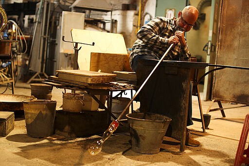 An artisan works in a glass factory at Murano island in Venice, Italy, Tuesday, March 3, 2020. G-7 countries say they are ready to take action to cushion the economic impacts of the new coronavirus outbreak, a statement that comes after a few days of wild market swings. (AP Photo/Francisco Seco)