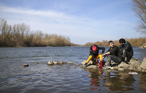 Migrants wash clothes at Maritsa river near Edirne, at the Turkish-Greek border on Monday, March 2, 2020. Thousands of migrants on Monday tried to find a way across the land border into Greece, which has made clear its borders will remain closed. Dozens managed to pass, either through border fences or across the river there. (AP Photo/Emrah Gurel)