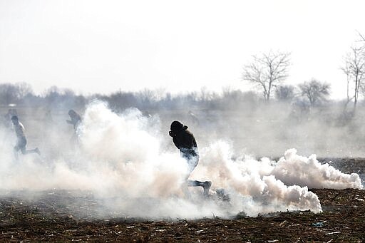 Migrants run to avoid tear gas thrown by Greek police during clashes near the Pazarkule border gate in Edirne, at the Turkish-Greek border on Monday, March 2, 2020. Thousands of migrants and refugees massed at Turkey's western frontier, trying to enter Greece by land and sea after Turkey said its borders were open to those hoping to head to Europe. (AP Photo/Darko Bandic)