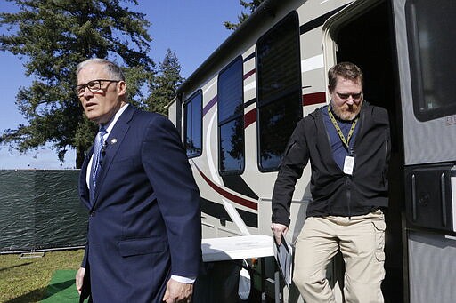 Washington Gov. Jay Inslee, left, leaves a recreation vehicle at a potential coronavirus isolation and quarantine site with Nathan Weed, incident commander for the coronavirus response team at Department of Health, Wednesday, March 4, 2020, in Centralia, Wash. Eight RVs are located at the site. The state has now reported 39 COVID-19 cases, all in the greater Seattle area, including 10 deaths. (AP Photo/Rachel La Corte)