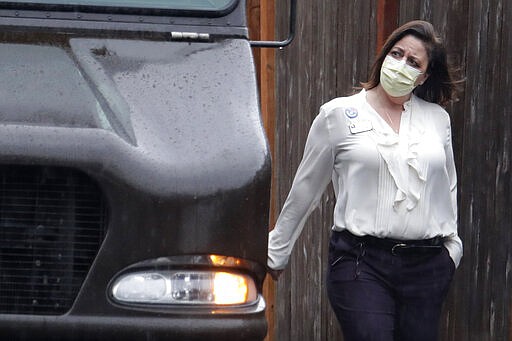 A worker at the Life Care Center in Kirkland, Wash., near Seattle, wears a mask as she walks near a UPS truck during a package delivery, Monday, March 2, 2020. Several of the people who have died in Washington state from the COVID-19 coronavirus were tied to the long-term care facility, where dozens of residents were sick. (AP Photo/Ted S. Warren)