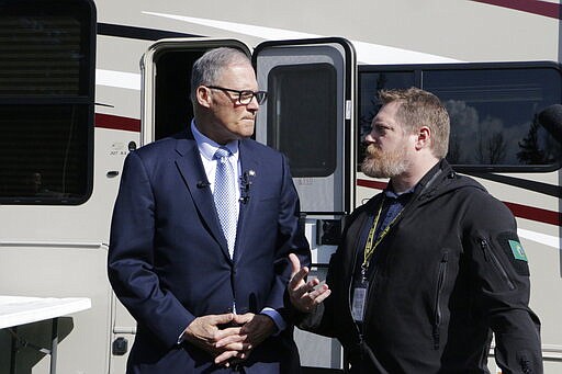 Washington Gov. Jay Inslee, left, talks with with Nathan Weed, incident commander for the coronavirus response team at Department of Health, outside a recreation vehicle at a potential coronavirus isolation and quarantine site, Wednesday, March 4, 2020, in Centralia, Wash. Eight RVs are located at the site. The state has now reported 39 COVID-19 cases, all in the greater Seattle area, including 10 deaths. (AP Photo/Rachel La Corte)