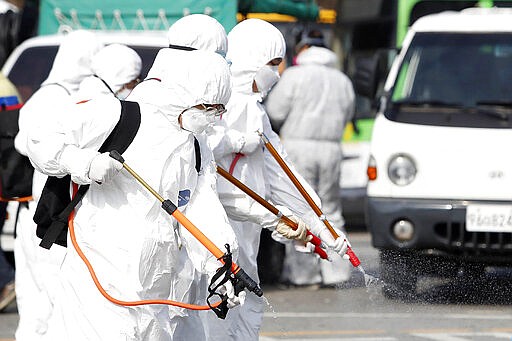 Workers wearing protective gears spray disinfectant as a precaution against the coronavirus at a bus garage in Gwangju, South Korea, Tuesday, March 3, 2020. China's coronavirus caseload continued to wane Tuesday even as the epidemic took a firmer hold beyond Asia. (Shin Dae-hee/Newsisvia AP)