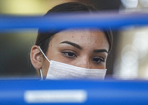 An airline agent wears a protective mask while printing out boarding passes at an airport check-in at the Arturo Merino Ben&iacute;tez International Airport, in Santiago, Chile, Tuesday, March 3, 2020. The health ministers of Argentina and Chile confirmed their respective country's first case of the coronavirus on Tuesday. (AP Photo/Esteban Felix)