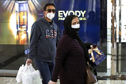 People wearing face masks and gloves shop at the Palladium Shopping Center, in northern Tehran, Iran, Tuesday, March 3, 2020. Iran's supreme leader put the Islamic Republic's armed forces on alert Tuesday to assist health officials in combating the outbreak of the new coronavirus, the deadliest outside of China. (AP Photo/Vahid Salemi)