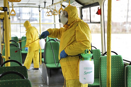 Employees wearing protective gear spray disinfectant to sanitize a passenger bus as a preventive measure against the coronavirus in Lviv, Ukraine, Tuesday, March 3, 2020. Ukrainian Chief sanitary and epidemiological doctor Viktor Liashko has just reported its first confirmed case of the new COVID-19 coronavirus, saying a man who recently arrived from Italy was diagnosed with the virus. (AP Photo/Mykola Tys)