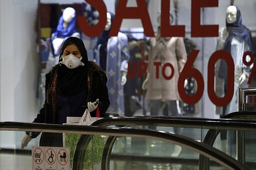 A woman wearing face mask and gloves shops at the Palladium Shopping Center, in northern Tehran, Iran, Tuesday, March 3, 2020. Iran's supreme leader put the Islamic Republic's armed forces on alert Tuesday to assist health officials in combating the outbreak of the new coronavirus, the deadliest outside of China. (AP Photo/Vahid Salemi)