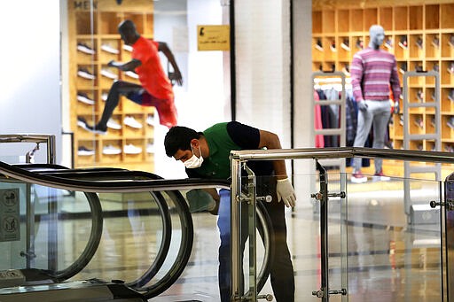 A worker wearing a face mask cleans and disinfects an escalator against coronavirus at the Palladium Shopping Center, in northern Tehran, Iran, Tuesday, March 3, 2020. Iran's supreme leader put the Islamic Republic's armed forces on alert Tuesday to assist health officials in combating the outbreak of the new coronavirus, the deadliest outside of China. (AP Photo/Vahid Salemi)