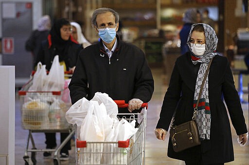 Shoppers wearing face masks and gloves shop at the Palladium Shopping Center, in northern Tehran, Iran, Tuesday, March 3, 2020. Iran's supreme leader put the Islamic Republic's armed forces on alert Tuesday to assist health officials in combating the outbreak of the new coronavirus, the deadliest outside of China. (AP Photo/Vahid Salemi)