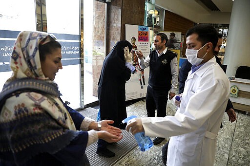 People have their temperature checked and their hands disinfected as they enter the Palladium Shopping Center, in northern Tehran, Iran, Tuesday, March 3, 2020. Iran's supreme leader put the Islamic Republic's armed forces on alert Tuesday to assist health officials in combating the outbreak of the new coronavirus, the deadliest outside of China. (AP Photo/Vahid Salemi)